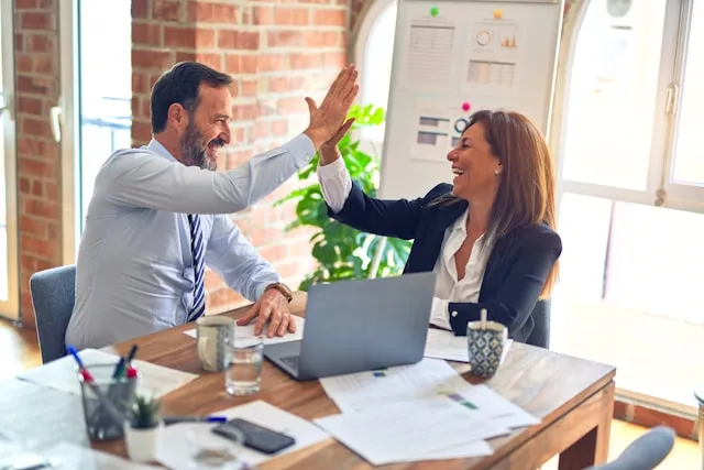 Two lawyers celebrating a result over case files at a desk